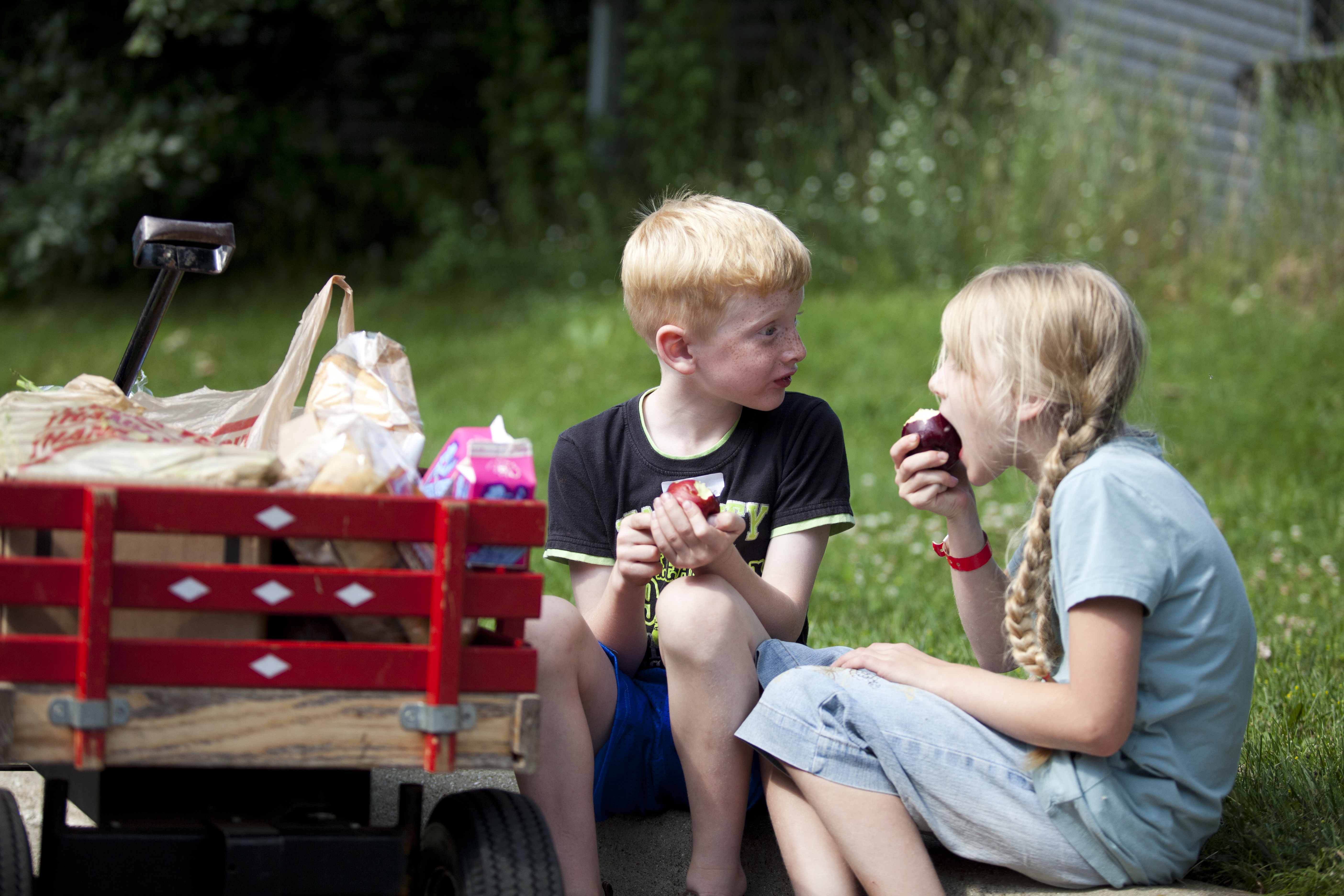 Boy and girl eating apples on a curb